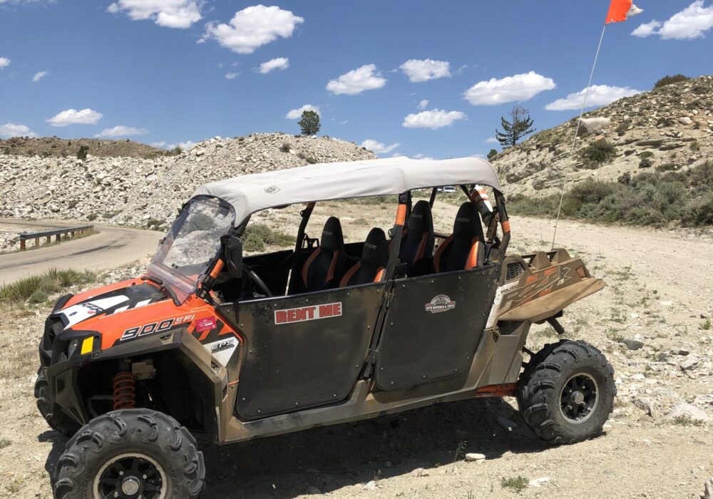 Orange 4-seat UTV parked on side of road